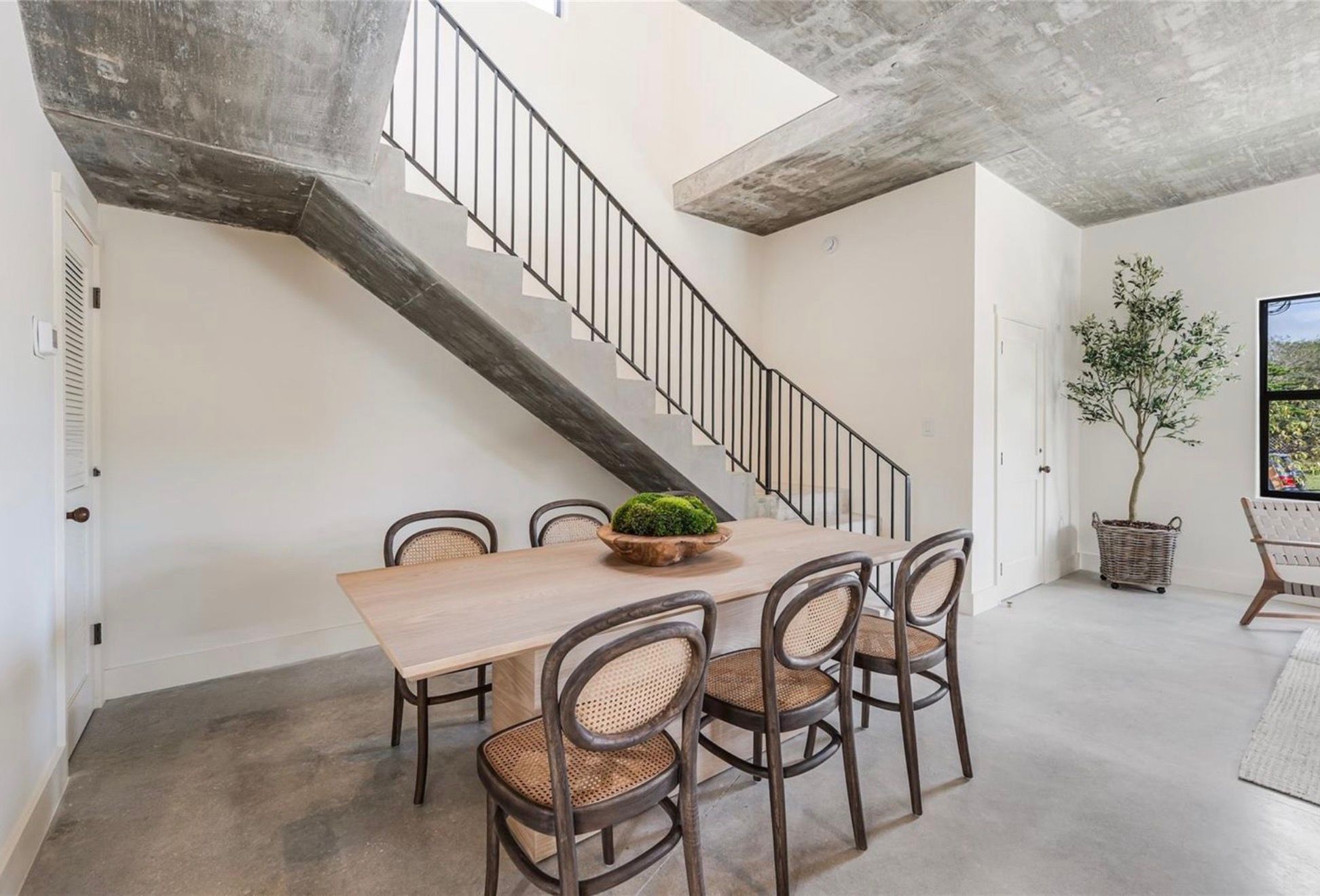Oak dining table beneath the concrete stair
